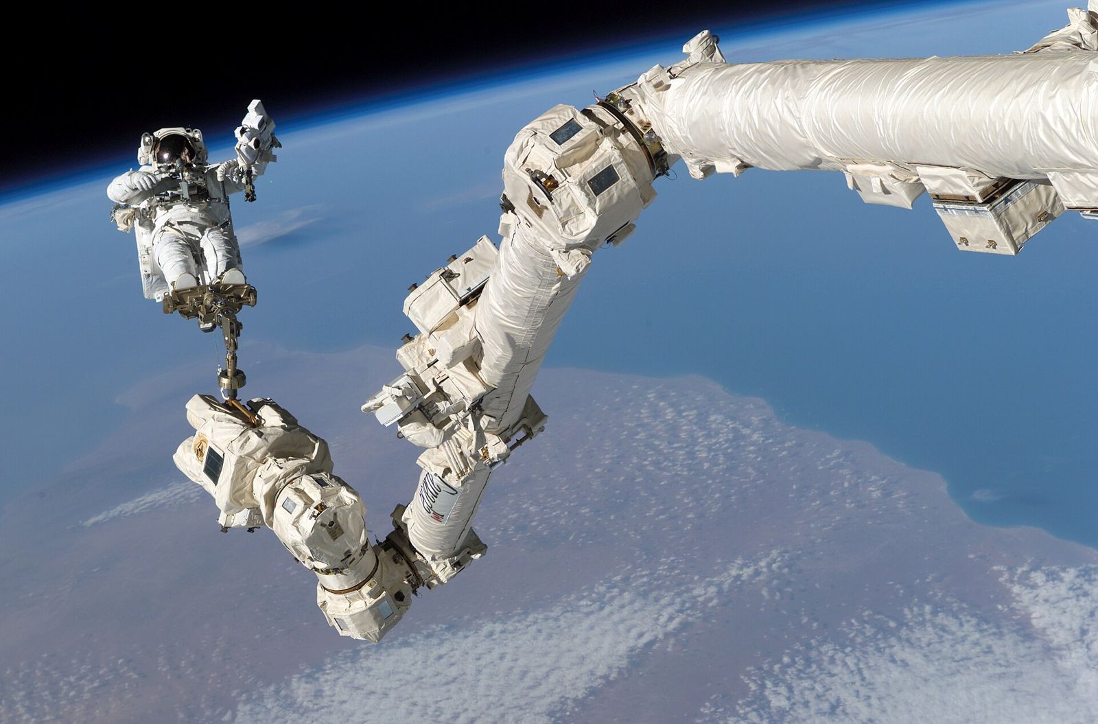 Robotic arm and engineer working in orbit